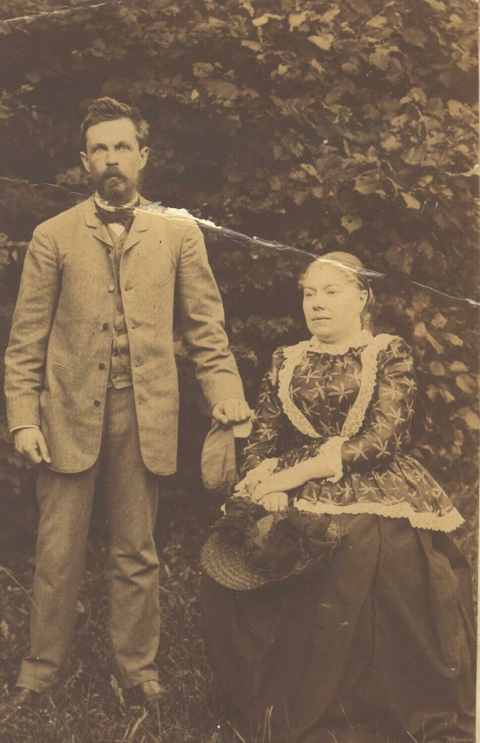 Старинное фото - мужчина с бородой стоит и женщина в платье сидит