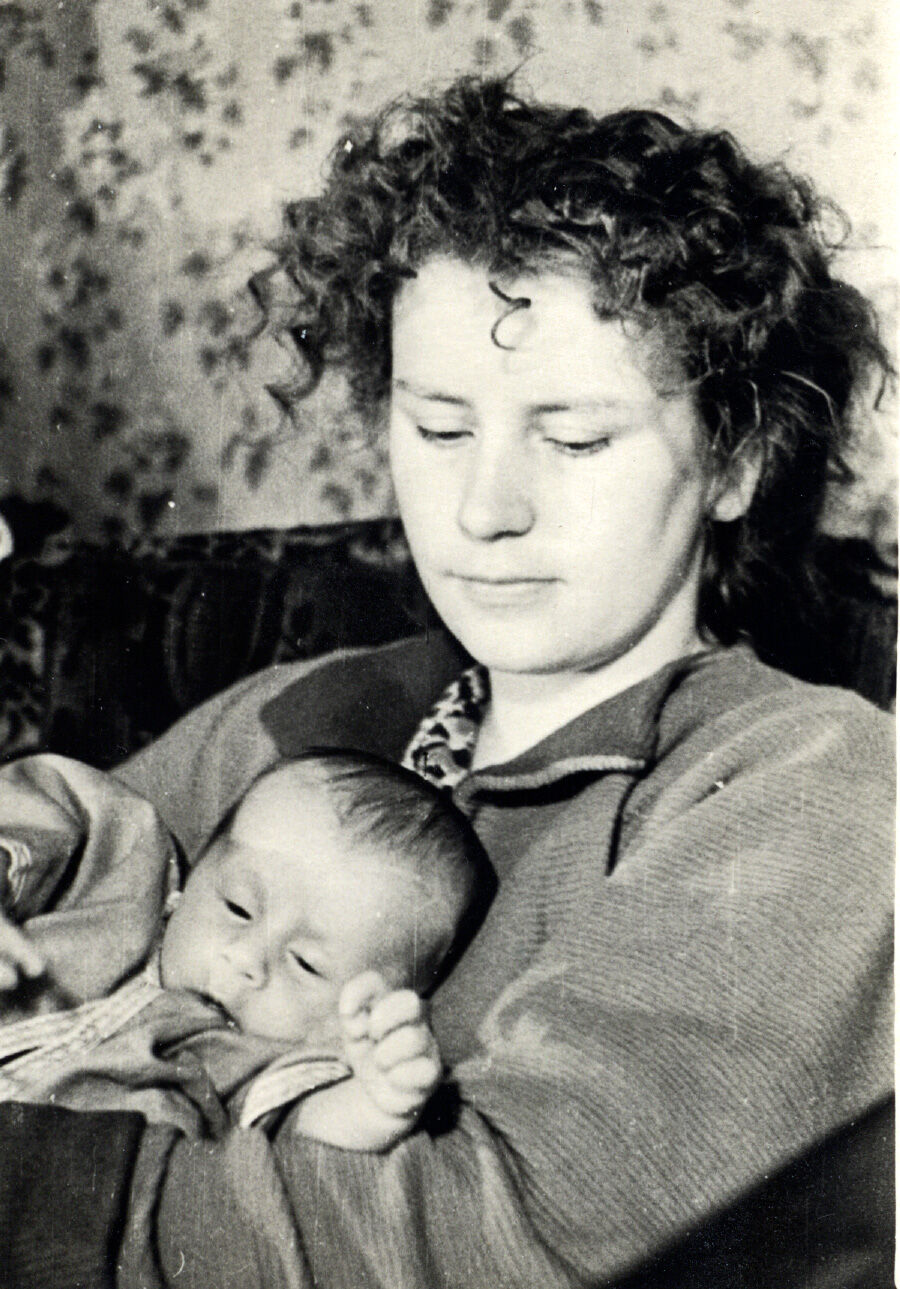 Черно-беловое изображение младенец на руках у молодой женщины с кудрявыми волосами