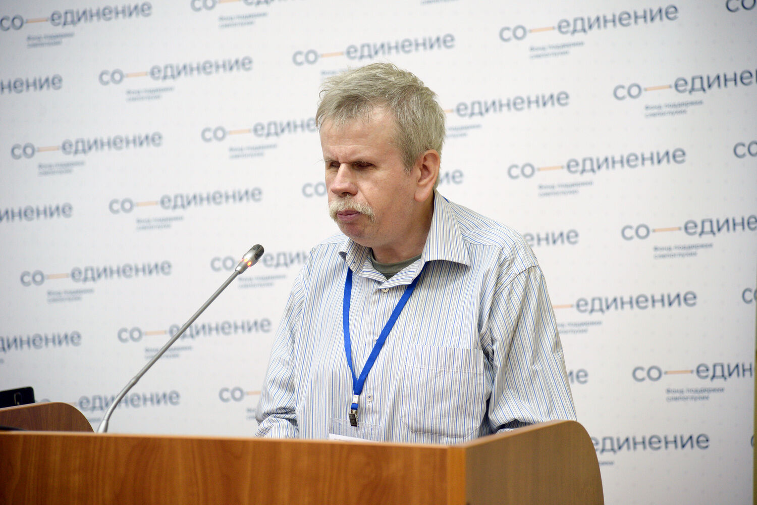 Андрей Андреевич Марков выступает с трибуны на заднем плане логотип фонда Со-единение